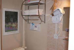 uma casa de banho com secador de cabelo e toalhas na parede em Hôtel le Dauphin em Moulins-la-Marche