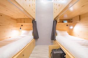 two beds in a small room with wooden walls at Norn Yaowarat Hotel in Bangkok