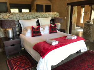 a bedroom with a large white bed with red pillows at Tinkers Lakeside Lodge - Kruger in White River