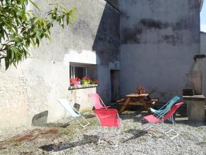 un groupe de chaises et une table devant un bâtiment dans l'établissement Le Gite à Nano, à Saint-Seurin-de-Cadourne