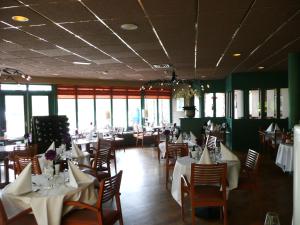 a dining room with white tables and chairs and windows at Kaapshoff 32 in Hollum