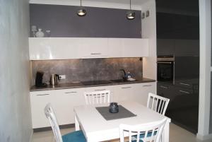 eine Küche mit einem weißen Tisch und weißen Schränken in der Unterkunft Apartament pod zamkiem in Olsztyn