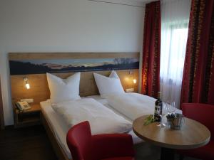 a bedroom with a bed with a table and a red chair at Hotel Seiserhof & Seiseralm in Bernau am Chiemsee
