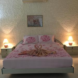 um quarto com uma cama com um cobertor rosa e 2 candeeiros em Peaceful homestay em Rawai Beach