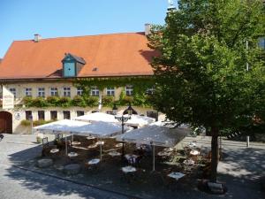 ein Gebäude mit Tischen und Sonnenschirmen davor in der Unterkunft Altstadt-Hotel Zieglerbräu in Dachau