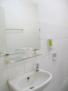 a white bathroom with a sink and a mirror at Hotel Tugu Asri in Jakarta