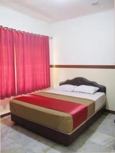 a bedroom with a bed with red curtains at Hotel Tugu Asri in Jakarta