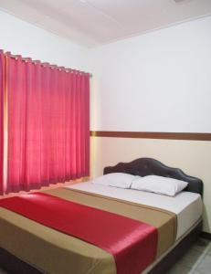 um quarto com uma cama com uma cortina vermelha em Hotel Tugu Asri em Jacarta
