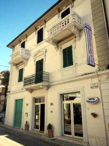 un edificio bianco con balconi su una strada della città di Hotel Conchiglia a Montecatini Terme