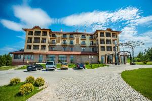 a large building with cars parked in a parking lot at SPA Hotel Splendor in Lubenia