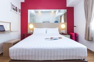 a bedroom with a large white bed and red walls at Monoloog Hotel Surabaya in Surabaya