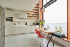 uma cozinha com uma mesa de madeira e cadeiras vermelhas em Lake View Apartment Amsterdam em Amsterdã