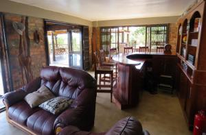 ein Wohnzimmer mit einem Ledersofa und einer Bar in der Unterkunft Buster's River Lodge in Marloth Park