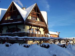 ein schneebedecktes Gebäude mit Schnee auf dem Boden in der Unterkunft Penzion Rotunda in Harrachov