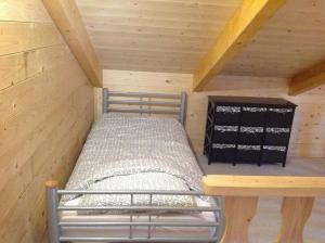 uma pequena cama num camarote com tecto em madeira em Hollands Oostenrijks huisje em Wieringerwerf