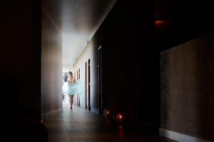 a woman in a white dress walking down a hallway at Ice House Hotel in Ballina