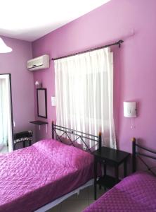 a purple bedroom with two beds and a window at Xenon Christina in Vivari
