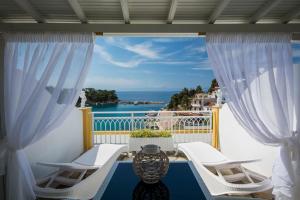 a balcony with white chairs and a view of the ocean at Pension Votsi in Votsi