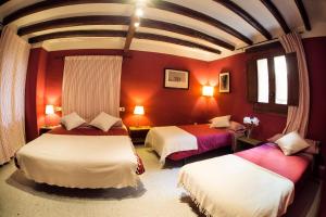 duas camas num quarto com paredes vermelhas em Lo Raconet de la Plaça em Calaceite
