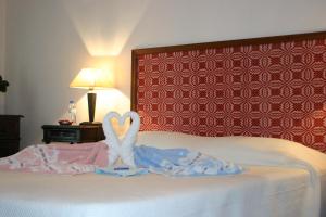 a bedroom with a bed with two swans making a heart at Urzelina GuestHouse in Urzelina