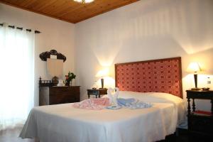 a bedroom with a white bed with a red headboard at Urzelina GuestHouse in Urzelina
