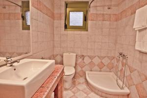 a bathroom with a sink and a toilet and a tub at Aselinos Suites in Koukounaries