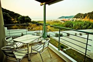a balcony with a table and chairs and a view of the beach at Aselinos Suites in Koukounaries