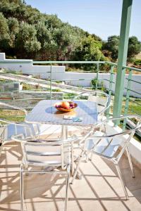 a table with chairs and a bowl of fruit on a balcony at Aselinos Suites in Koukounaries