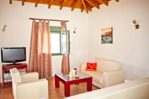 a living room with white furniture and a tv at Aselinos Suites in Koukounaries