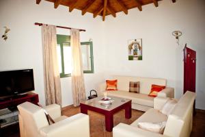 a living room with white furniture and a tv at Aselinos Suites in Koukounaries