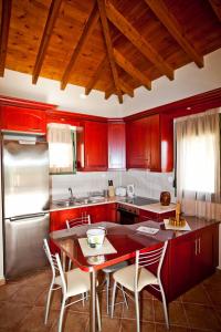 a kitchen with red cabinets and a table with chairs at Aselinos Suites in Koukounaries