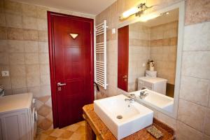 a bathroom with a white sink and a red door at Aselinos Suites in Koukounaries