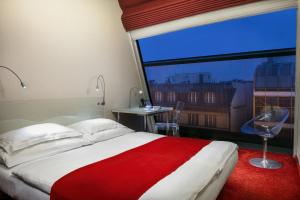 a bedroom with a red and white bed and a window at Design Metropol Hotel Prague in Prague