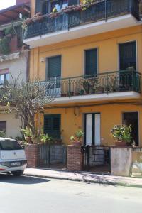 タオルミーナにあるCasa vacanze "Terra del sole"の黄色の建物(バルコニー付)と正面に駐車