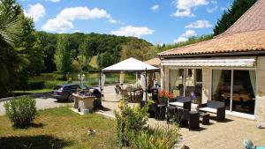 une maison avec une tente et une voiture garée devant elle dans l'établissement Les Gites de l'Etang de Sandanet, à Issac