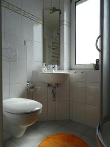 ein Badezimmer mit einem WC, einem Waschbecken und einem Spiegel in der Unterkunft Ferienwohnungen Damm in Kassel