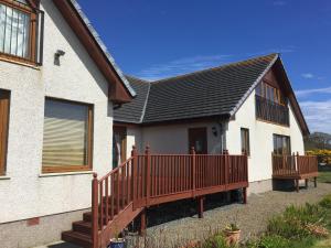 a house with a wooden deck on the side of it at Acarsaid B&B in Lybster