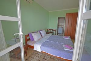 1 dormitorio con 1 cama con almohadas moradas y blancas en Apartments Cejovic, en Ulcinj