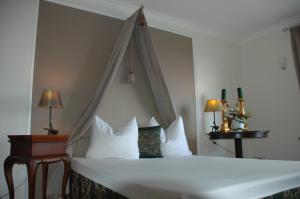 a bedroom with a white bed with a canopy at Landsitz Kapellenhöhe, Hotel Garni in Wiedenbrügge