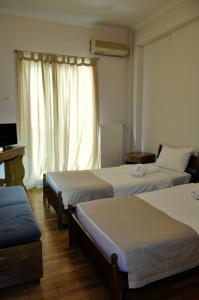 アテネにあるAchillion Apartmentのベッド3台と窓が備わるホテルルームです。