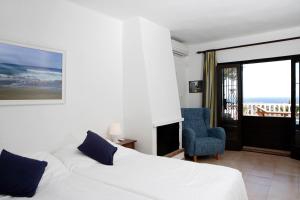 a bedroom with a white bed and a blue chair at Can Carlos Ibiza in Sant Jordi