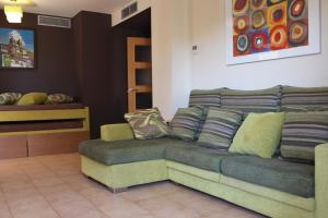 a couch with pillows on it in a room at Apartamento con piscina a 300m playa Fenals-Lloret in Lloret de Mar