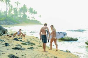 a man and woman standing on a beach with a surfboard at Villa Océane in Mirissa