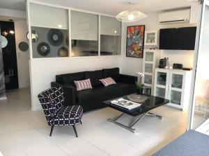 a living room with a black couch and a table at Cap Locations Naturisme in Cap d'Agde