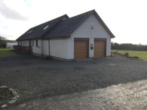 a white building with two garage doors on a driveway at Acarsaid B&B in Lybster