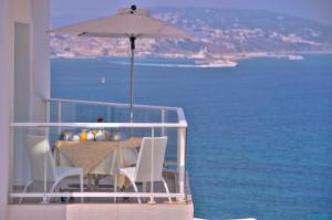 a table with an umbrella on a balcony with the ocean at Hotel Farah Tanger in Tangier