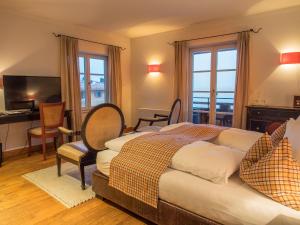 a bedroom with two beds and a desk and a television at Seehotel Luitpold in Tegernsee