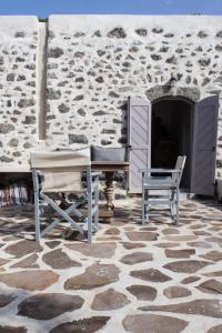 a patio with a table and chairs and a stone wall at Kafka Stone House in Emporeiós