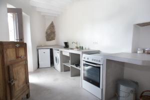 a white kitchen with a sink and a stove at Kafka Stone House in Emporeiós
