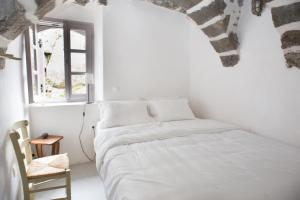 a white bedroom with a bed and a window at Kafka Stone House in Emporeiós